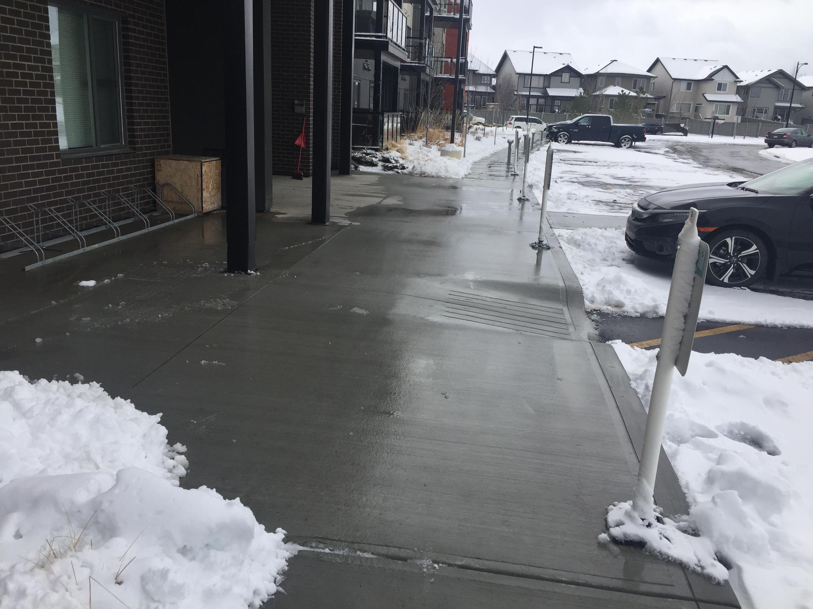 Commercial property sidewalk cleared with snow piled to sides and building entrance